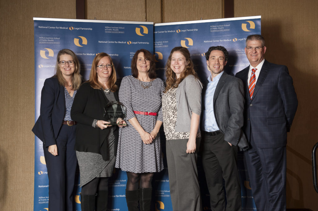 Erin Loubier (second from left) and Megan Coleman (fourth from left) accepting the 2016 Outstanding MLP Award on behalf of Whitman-Walker Health. Also pictured: staff and Advisory Council members from the National Center for Medical-Legal Partnership.